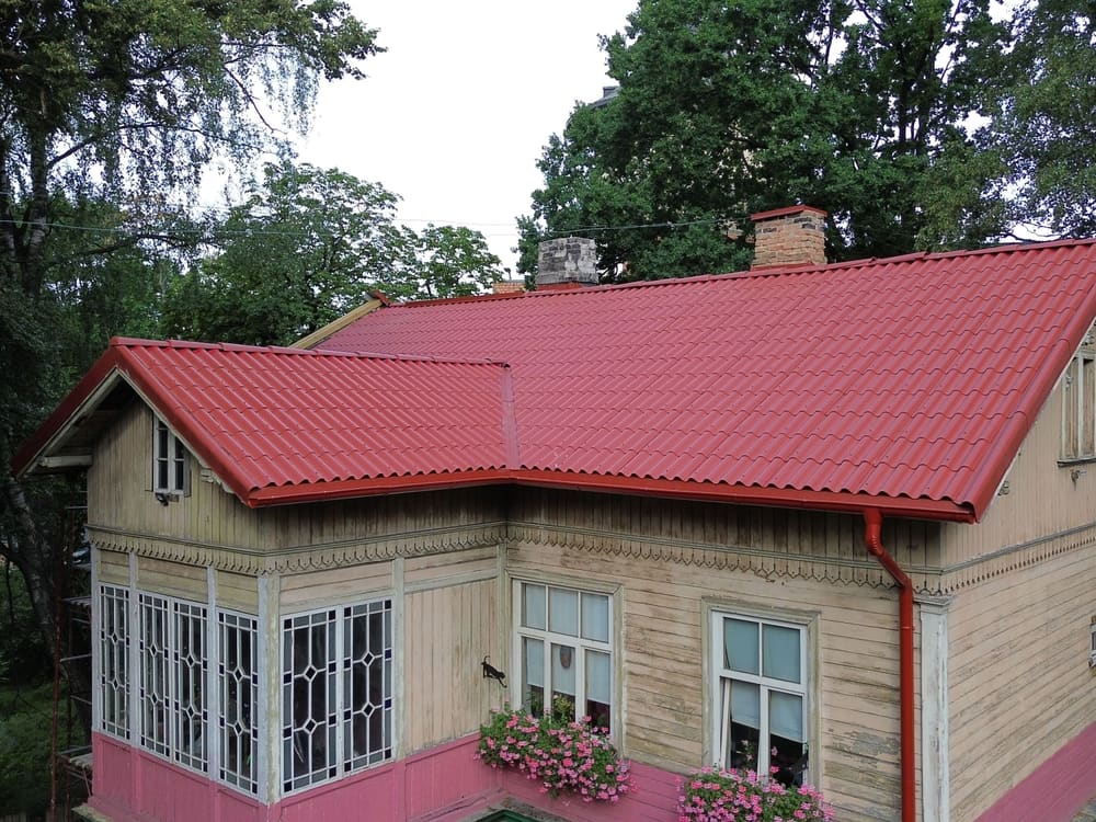 Koka māja ar sarkanu metāla dakstiņu jumtu
